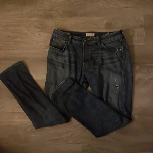 Mörkblå jeans Slim Glenn Jack and Jones - Snygga mörkblå jeans i modellen Slim Glenn. De har en slim passform och är tillverkade i ett klassiskt denimtyg. Jeansen har en sliten detalj på ena benet för en trendig look. Perfekta för en avslappnad stil. Säljer dem för 150men kan gå en liten bit mindre beror på