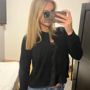 Svart kofta från H&M - Säljer en stilren svart kofta från H&M. Koftan har långa ärmar och knappar framtill, perfekt för en enkel och klassisk look.  Passar också både för s och m