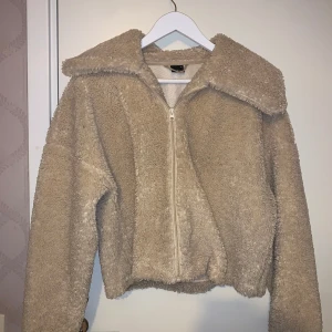 Beige teddyjacka från Gina Tricot - Mysig beige teddyjacka från Gina Tricot med dragkedja framtill. Jackan har en stor krage och långa ärmar, perfekt för kyliga dagar.  Den är ganska använd men ser forfarande väldigt bra ut! 😄