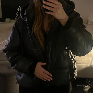 Svart pufferjacka från Zara - Säljer en svart pufferjacka från Zara. Jackan har en luva och dragkedja framtill. Perfekt för kyliga dagar och ger en trendig look. Passar bra till både jeans och leggings. Storlek L men passar mer M. Slutsåld på Zaras hemsida. Använd 1 vinter. 
