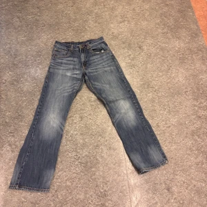 Blå jeans med broderade bakfickor - Säljer ett par klassiska blå jeans med snygga broderade detaljer på bakfickorna. De har en straight passform och är tillverkade i bomull för en bekväm känsla. Perfekta för en avslappnad stil.