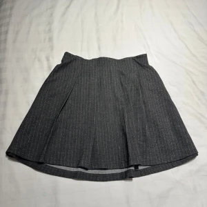 Grå kjol med ränder - Snygg grå kjol med diskreta ränder. Kjolen har en elastisk midja för extra komfort och en klassisk design som passar till många tillfällen. Ny med prislapp i storlek S. Nypris 179kr skriv vid intresse