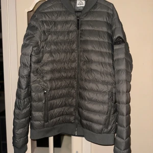 Dunjacka från Mckinley - Snygg grå quiltad jacka med dragkedja framtill.