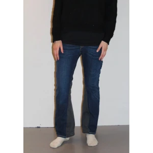 Blå jeans från Levi's - JEANS 016: Snygga, mörkblåa, lågmidjade jeans från Levi’s med utsvängda/utsydda ben.  Midjemått: 74,5 cm. Innerbenslängd: 71,5 cm. 