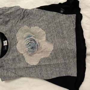 Grå t-shirt med blomtryck från Molo - Säljer en grå t-shirt från Molo med ett stort blommönster i mitten. T-shirten har korta ärmar och en rund halsringning. Perfekt för en avslappnad stil. Den kommer tvättas och strykas innan den skickas! ⭐️