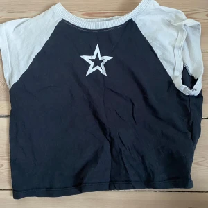 Svart och vit crop top från H&M - Säljer en cool svart och vit crop top från H&M med en stjärna framtill! 