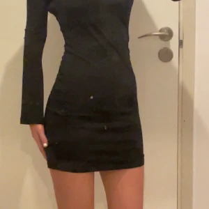 Svart klänning från BikBok - Snygg svart klänning från BikBok i tight passform. Klänningen är långärmad och kort, perfekt för en stilren look. Tillverkad i ett mjukt och stretchigt material som sitter bekvämt. Dubbeltyg så 0 genomskinlighet. 