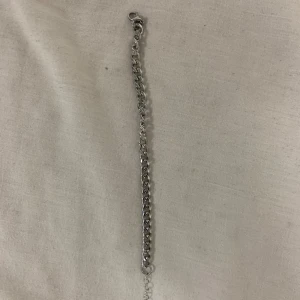 Silverfärgat armband - Snyggt silverfärgat armband med kedjedesign. Perfekt för att ge en stilren touch till din outfit. Armbandet har en justerbar kedja för att passa olika storlekar.