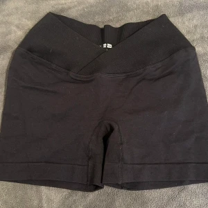 Svarta gymshorts med V-formad midja - Snygga svarta träningsshorts med en V-formad midja, de ger en illusion av en smalare midja. Perfekta för träning eller gym. De är tillverkade i ett stretchigt material som ger en bekväm passform. Oanvända i fint skick❤️⚠️sömmen som syns på bilden syns ej när man har på sig shortsen, sömmen följer innersidan av låret🥰⚠️
