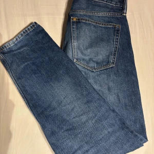 Blå jeans från H&M - Säljer ett par blå jeans från H&M med relaxed fit. De har en klassisk femficksdesign och stängs med knapp och dragkedja. Perfekta för en avslappnad stil.