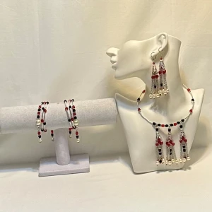 Smyckesset med pärlor i rött, svart och vitt - Elegant smyckesset med halsband, armband och örhängen. Designen har pärlor i rött, svart och vitt med hängande detaljer. Perfekt för att ge en färgklick till din outfit.Ett par örhängen och ett par armband plus en halsband handgjorda mycket mycket fint nytt oanvänd 
