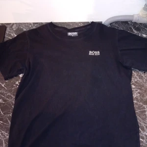 SVART HUGO BOSS T-SHIRT - Hej!, säljer en svart HUGO BOSS t-shirt i st.S det finns inga tydliga defekter på t-shirten, men den är lite fläckig på bak- framsida det kan man se på bild 1 och 4.
