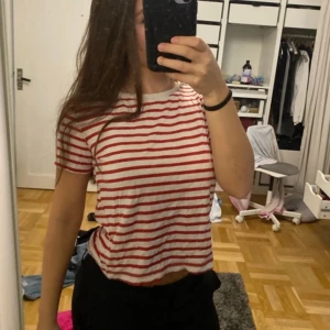 Randig t-shirt från Zara - Säljer en randig t-shirt från Zara i rött och vitt. Den har en normal passform och korta ärmar, perfekt för en avslappnad stil. T-shirten är tillverkad i ett mjukt material som känns skönt mot huden.