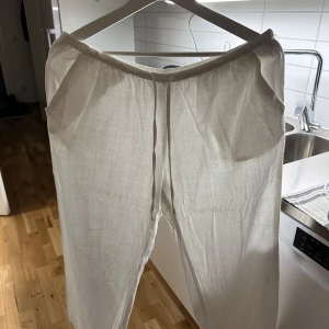 Vita linnebyxor - Snygga och luftiga vita linnebyxor perfekta för varma dagar. De har en avslappnad passform och elastisk midja för extra komfort. Perfekta för en stilren och bekväm look.