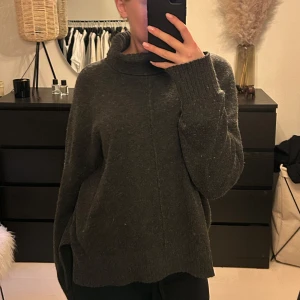 Mörkgrå polotröja - Säljer en mysig mörkgrå polotröja med långa ärmar och ribbade muddar. Perfekt för kyliga dagar och ger en stilren look. Tröjan har en lös passform och är tillverkad i ett mjukt material. Köpt på nelly för några år sedan