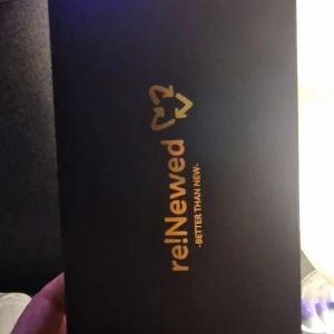Samsung smartphone i reNewed-förpackning - Säljer en Samsung smartphone i en elegant reNewed-förpackning. Telefonen har en stilren design med en mörk baksida och en stor skärm. Perfekt för dig som vill ha en pålitlig och snygg mobil.