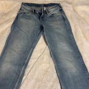 Blå jeansbyxor - Snygga blå jeansbyxor med klassisk femficksdesign och ljus tvätt. De har en rak passform och är perfekta för en avslappnad stil. Byxorna har en knappgylf och bälteshällor. Stl W27/L32. Längd 100cm och 35cm bred från ficka till ficka