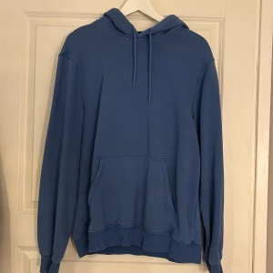 Blå hoodie - Säljer en blå hoodie i stl S. Den har en avslappnad passform med en klassisk känguruficka och justerbar huva. Perfekt för en casual look.