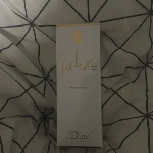 J'adore Eau de Parfum från Dior helt ny - Elegant och tidlös parfym från Dior, J'adore Eau de Parfum. Förpackningen är stilren i vitt med gyllene detaljer. Perfekt för den som älskar lyxiga och feminina dofter.