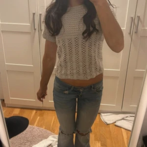 Beige stickad topp - Säljer en söt beige stickad topp med korta ärmar. Perfekt för en avslappnad stil med ett fint mönster som ger en luftig känsla. Använd fåtal gånger