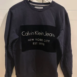 Mörkblå sweatshirt från Calvin Klein Jeans - Snygg mörkblå sweatshirt från Calvin Klein Jeans med tryck 'New York City Est 1978' på bröstet. Tröjan har rund hals och långa ärmar, perfekt för en casual look.