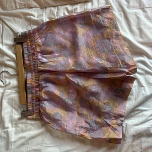 Färgglada shorts med mönster - Säljer ett par färgglada shorts med ett abstrakt mönster i rosa, lila och gult. De har en elastisk midja för extra komfort. 