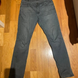 Grå jeans Slim/Glenn - Snygga grå jeans i slim fit-modell från Jack and Jones Slim/Glenn. De har en klassisk femficksdesign och dragkedja. Perfekta för en stilren look.
