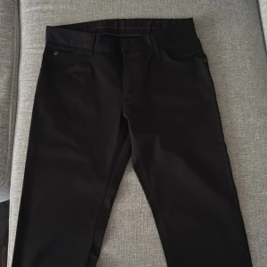 Svarta byxor med dragkedja - Snygga svarta byxor med dragkedja och knappar. De har en klassisk design med fickor både fram och bak. Perfekta för en stilren look.