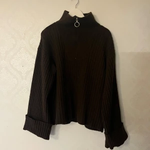 Brun ribbad tröja med dragkedja - Säljer en brun ribbad tröja med dragkedja och hög krage. Tröjan har vida långa ärmar och en avslappnad passform.