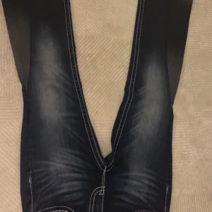 Mörkblå jeans från Miss Me - Snygga mörkblå jeans från Miss Me med coola broderade detaljer på bakfickorna. De har en klassisk femficksdesign och kontrastsömmar som ger en unik look. Perfekta för dig som vill ha något extra i garderoben!