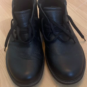 Svarta skinnkängor från Ecco - Säljer ett par svarta kängor från Ecco i skinn med snörning. Skorna har en robust sula och är perfekta för höst och vinter. De är märkta med Gore-Tex vilket gör dem vattentäta och hållbara. Kängorna är i storlek 45 (innersula saknas och skorna är i nyskick)