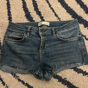 Blå jeansshorts från Zara - Snygga blå jeansshorts från Zara med fransiga kanter. Perfekta för sommaren.De har en knapp och dragkedja framtill, super sköna och stretchiga. Har ett litet hål men de är inget som man ser när de sitter på. Storlek s