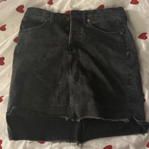 Svart jeanskjol - Snygg svart jeanskjol med rå kant och klassisk femficksdesign. Perfekt för en avslappnad stil. Från lager 157 i storlek M