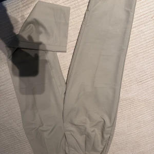 Beige kostymbyxor med knappar - Snygga beige kostymbyxor med stilrena knappar i midjan. Perfekta för en elegant look. Byxorna har en klassisk passform och är tillverkade i ett bekvämt material.