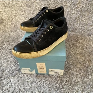 Lanvins - Snygga svarta sneakers med glänsande lackdetaljer på tån och en krämfärgad sula. Skorna har snörning och en stilren design som passar perfekt för en trendig look.