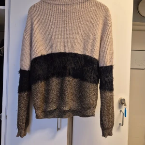 Beige stickad tröja från Lindex - Säljer en mysig beige stickad tröja från Lindex med en unik design. Tröjan har en mörkare sektion i mitten med en fluffig textur och långa ärmar. Perfekt för kyliga dagar!