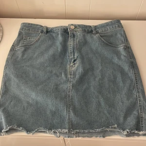 Jeanskjol från H&M - Snygg jeanskjol från H&M i klassisk blå denim. Kjolen har en rå kant nertill och femficksdesign med knapp och dragkedja framtill. Perfekt för en avslappnad stil🩵sitter som en M-L med väldigt stretchigt material🩵