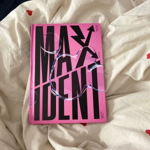 MAXIDENT - En bok med titeln 'MAXIDENT' i stora svarta bokstäver på ett rosa omslag. Omslaget har en modern och iögonfallande design med en glansig yta. Perfekt för den som gillar stilrena och färgglada böcker.