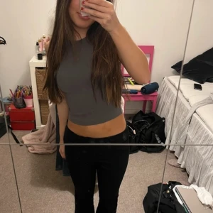 Grå ärmlös croppad topp - Säljer en stilren grå ärmlös croppad topp. Perfekt för en avslappnad look. Toppen har en tight passform och är tillverkad i ett mjukt material.