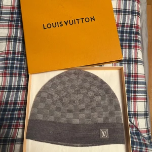 Grå mössa från Louis Vuitton - Riktig Snygg grå mössa från Louis Vuitton, (Äkta!)   inget kvitto men lådan medföljer såklart, säljer pågrund av att jag har en annan mössa och tröttnat på denna. Perfekt för att hålla dig varm i denna kalla vinter och snön!!! Står ej för postens slarv! Små små skador finns på sista bilden som jag ringat in! Skicka gärna bud/prisförslag!