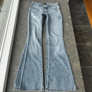 Lågmidjade bootcut jeans  - Snygga blå bootcut jeans med broderade detaljer på bakfickorna. De har en klassisk femficksdesign och en knappgylf. Perfekta för en avslappnad stil med en touch av retro. Midjemått tvärs över är 36 och innerbenslängden runt 80cm