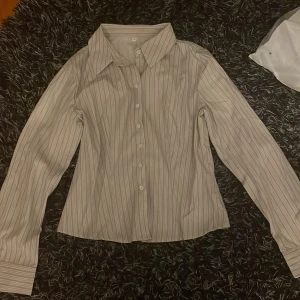 Randig skjorta med långa ärmar - Snygg och stilren randig skjorta med långa ärmar och knappar framtill. Perfekt för en klassisk look.