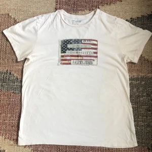 Ralph Lauren Denim&Supply t-shirt - En otroligt elegant och snygg Ralph Lauren denim&supply T-shirt med ett tryck med en USA flagga i sliten design i ett mycket fint skick! Storleken är L men sitter som en M! Hör av dig vid eventuella frågor eller funderingar!