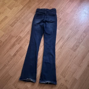 Mörkblå bootcut jeans - Snygga mörkblå bootcut jeans med hög midja och klassisk femficksdesign. Perfekta för en avslappnad stil med en touch av retro. De har en dragkedja och knapp framtill.