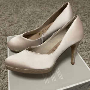 Eleganta pumps från Tamaris - Snygga pumps i ljusrosa satin från Tamaris med glittrig klack och platåsula. Perfekta för en elegant look med spetsig tå och bekväm passform. motsvarar storlek 36,5-37!