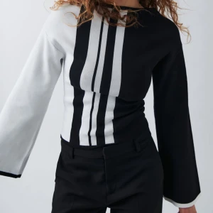 Svart och vit tröja - Säljer denna snygga stickade svart och vit-randiga tröja. Tröjan har långa vida ärmar och båtringning i halsen. Supermjuk och elegant, använd endast en gång!