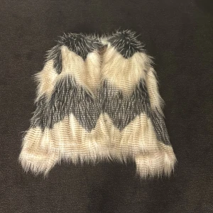 Mönstrad pälsjacka från Esprit - Säljer en cool och fluffig pälsjacka från Esprit med ett unikt mönster i svart och beige. Jackan är perfekt för att ge din outfit en extra edge. Den har en mjuk insida och är supermysig att ha på sig.