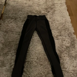 Svarta leggings med mönstrade detaljer - Snygga svarta leggings med diskreta mönstrade detaljer längs benen. Perfekta för en stilren look med en twist. De har en tight passform och är bekväma för både vardag och träning.