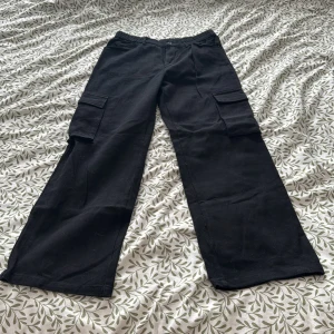 Svarta cargopants - Snygga svarta cargopants med breda ben och praktiska fickor på sidorna. Perfekta för en avslappnad stil. De har en elastisk midja för extra komfort.