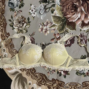 Gul spets-bh från Intimissimi - Elegant beige bh från Intimissimi med vacker spetsdetaljering. Bh:n har justerbara axelband och en klassisk hakknäppning bak. Perfekt för en sofistikerad look. 75B